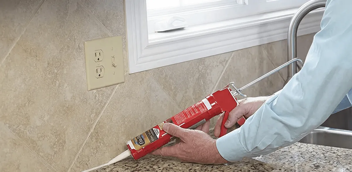 Handyman applying caulk along a kitchen backsplash and countertop seam in Provo, UT